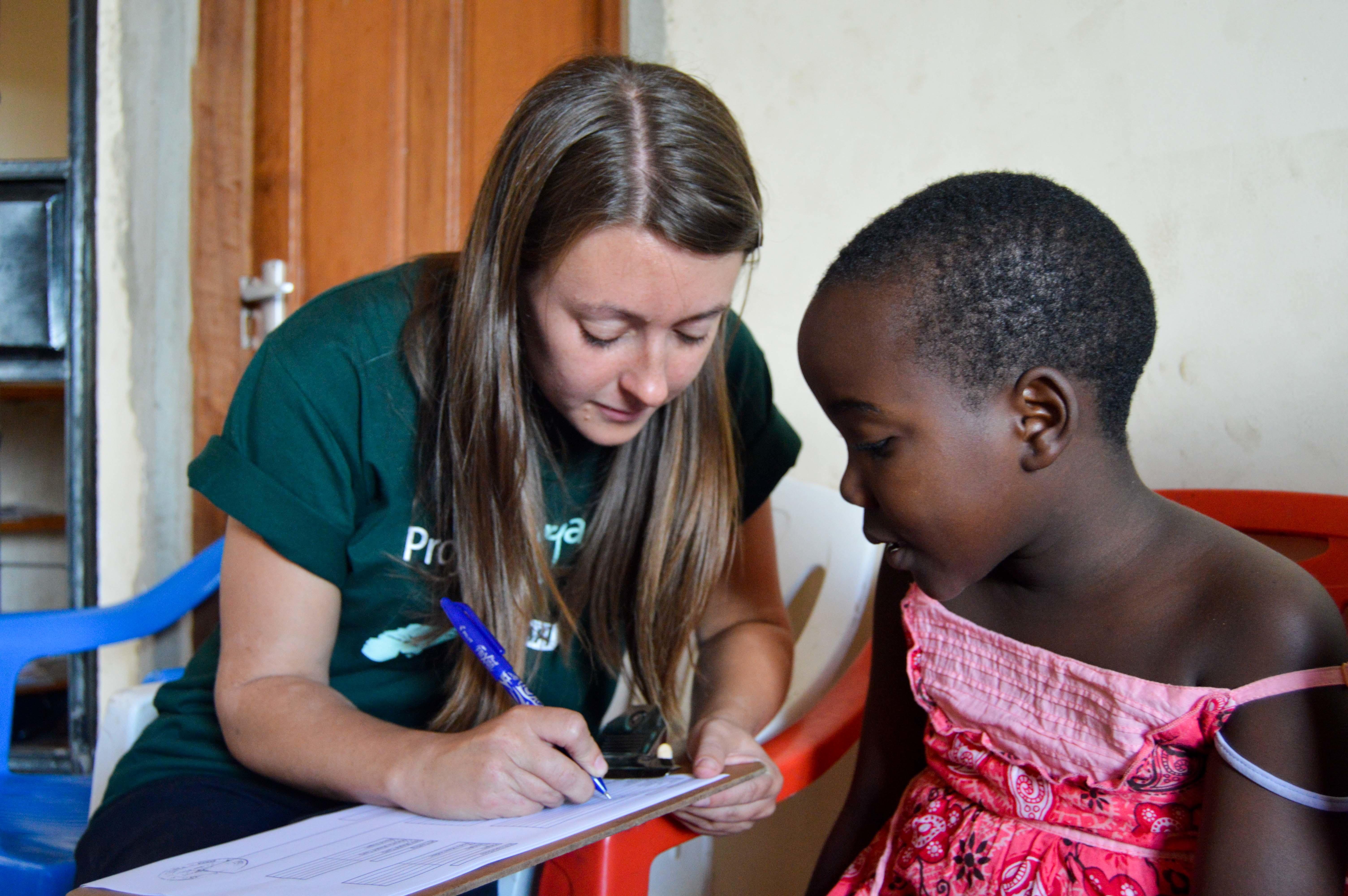Pasante de Medicina en Tanzania toma los datos de una pequeña paciente. Pasante registrando información de paciente durante su pasantía médica en Tanzania.